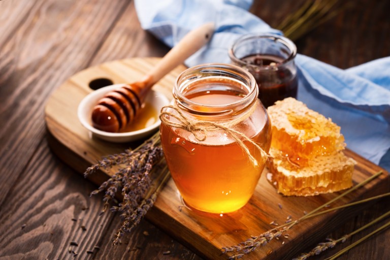 мед в стеклянной баночке рядом с сотами